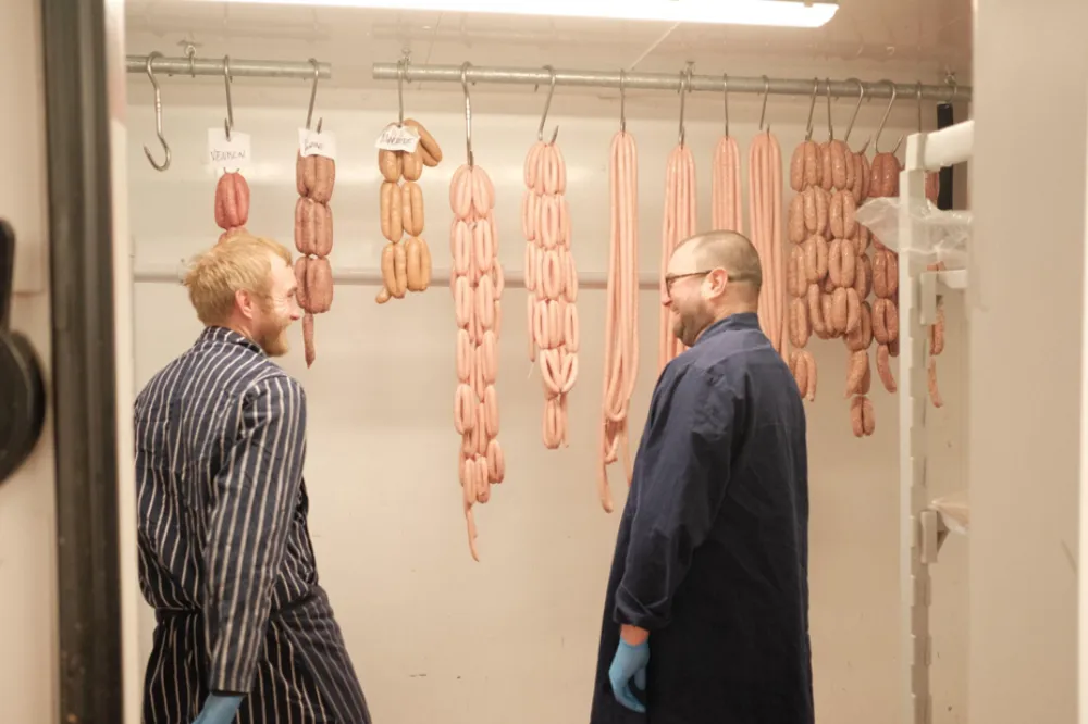 Family butcher | two butchers in a walk-in cold room with sausages hanging in the background.